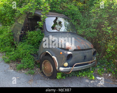 Genua Italien April 25, 2018: Vintage rusty Fiat 500 in schlechtem Zustand verlassen und durch die Vegetation eingetaucht Stockfoto