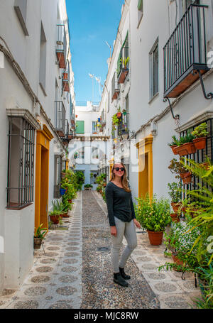 Touristische in einer Gasse mit Blumen und Pflanzen mit weißen Häuser geschmückt, Calle Indiano, Cordoba, Provinz Córdoba, Andalusien, Spanien Stockfoto