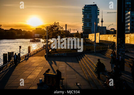 Berlin, Deutschland - Mai, 2018: die Menschen am Flußufer an der Berliner Mauer/East Side Gallery in Berlin Deutschland bei Sonnenuntergang im Sommer Stockfoto