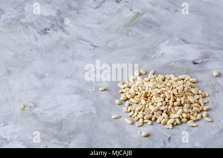 Stapel von peelled Erdnüsse auf weiße strukturierte Hintergrund, Hintergrund, Ansicht von oben, Nahaufnahme, selektiven Fokus. Organische nahrhafte Zutat. Gourmet Stockfoto