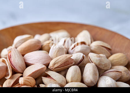 Gesalzene Pistazien auf einer Holzplatte auf weißem Hintergrund, Ansicht von oben, Nahaufnahme, selektiven Fokus. Leckere bio Snack. Gesunde Ernährung für ein gesundes Leben. Fo Stockfoto