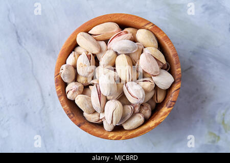 Gesalzene Pistazien auf einer Holzplatte auf weißem Hintergrund, Ansicht von oben, Nahaufnahme, selektiven Fokus. Leckere bio Snack. Gesunde Ernährung für ein gesundes Leben. Fo Stockfoto