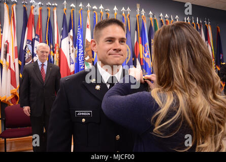 Zweiter Leutnant Jakob Johnson ist mit Leutnant Bars von seiner Frau festgesteckt, nachdem Sie den Amtseid während seiner Officer Candidate School graduation April 29, 2018, am Fort Pickett, Virginia. Johnson vor kurzem abgeschlossene OCS als Teil der OCS-Klasse 61 des Virginia National Guard A. Johnson, der militärische Geheimdienst verzweigt und wird als Taktischer Offizier mit Intel-basierten Portsmouth 2nd Squadron, 183Rd Kavallerie Regiments, 116 Infantry Brigade Combat Team dienen. (U.S. Army National Guard Foto von Sgt. 1. Klasse Terra C. Gatti) Stockfoto