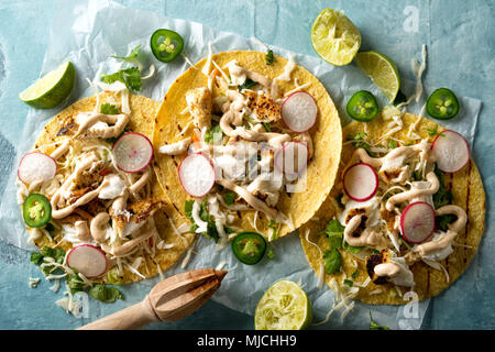 Leckere Tacos mit gegrilltem Fisch, Koriander, Limette, Kohl, Karotten, Jalapeno und Rettich mit mexikanischen Chili Sauce Crema. Stockfoto