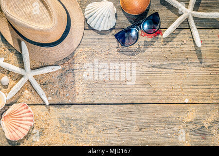 Sommer Accessoires wie Hut, Muscheln und Sonnenbrille auf Holz- und Sandy Hintergrund Stockfoto
