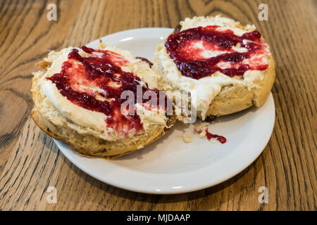 Nahaufnahme von Scones mit Clotted Cream und Himbeermarmelade gekrönt. Stockfoto