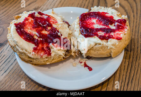 Nahaufnahme von Scones mit Clotted Cream und Himbeermarmelade gekrönt. Stockfoto