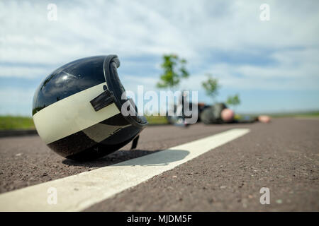 Biker Helm liegt auf der Straße in der Nähe von einem Motorradunfall Stockfoto