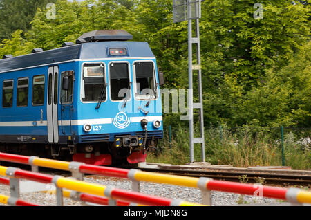 Djursholm, Schweden - 15. Juli 2016: Mit der S-Bahn auf der Roslagsbanan Zeile 29 mit Destination Stockholm Ostra passieren den Bahnübergang mit gefalteten Boo Stockfoto