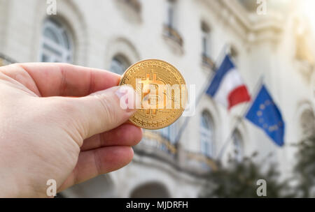 Hand mit goldenen Bitcoin gegen Flaggen von Frankreich und der Europäischen Union, Konzept Stockfoto