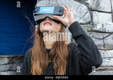 Frau mit Virtual reality Headset zu sehen die Skellig Rocks, im County Kerry, Irland von Valentia Island Visitor Centre, von Failte Ireland Tourismus organisieren, während die 4. Bank Holiday Wochenende Stockfoto