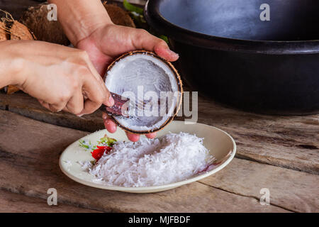 Frau mit Hand kratzen Coconut stellen Sie den Behälter für den Nachtisch machen und Essen. Stockfoto