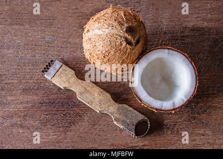 Das Werkzeug für die Verschrottung der Kokosnuss Fleisch klein auf Holz. Ansicht von oben Stockfoto