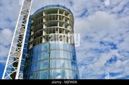 Bau eines neuen Glas zylindrisches Hochhaus mit Kran gegen ein bewölkter Himmel Stockfoto