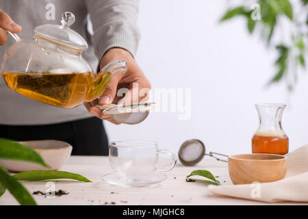 Aus einer Teekanne Tasse Tee auf einem Holztisch gegossen Stockfoto