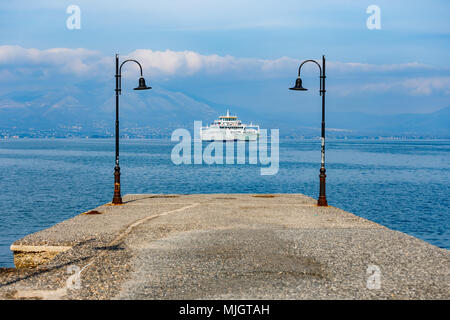Fähre über das Meer reisen mit Pier Lampen Framing der Szene gegen einen bewölkten Himmel in Griechenland Stockfoto