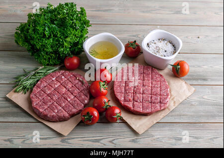 Die koteletts für Burger aus frischem Hackfleisch mit Gewürzen ende Kräutern auf einem Holztisch Stockfoto