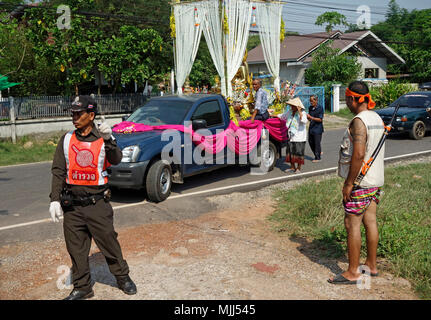 Songkran Thai Neujahr, Polizist steuert Verkehr für Pickup Lkw mit goldenen Buddha Statue, Mönch und Dekorationen, Udon Thani, Isaan, Thailand Stockfoto