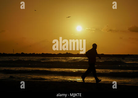 Silhouette einer Jogger auf das Mittelmeer bei Sonnenuntergang. Fotografiert in Tel Aviv, Israel Stockfoto