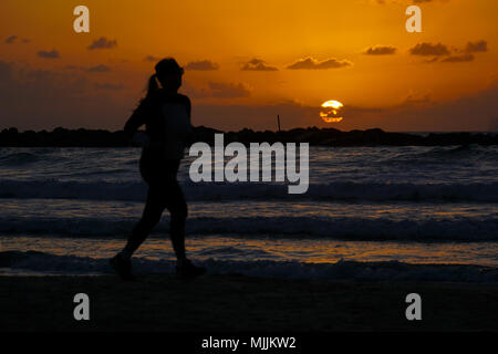 Silhouette einer Jogger auf das Mittelmeer bei Sonnenuntergang. Fotografiert in Tel Aviv, Israel Stockfoto