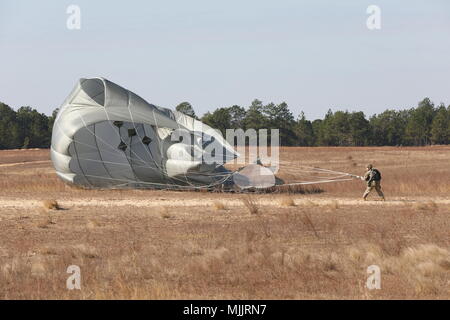Die Operation Toy Drop 2017 fand am 1. Dezember 2017 in der Sicily Drop Zone in Fort Bragg, North Carolina, unter dem United States Army Civil Affairs & Psychological Operations Command (Airborne) statt. Das Archivbild dokumentiert einen Fallschirmjäger der US-Armee, der der 108th Military Police Company zugeteilt wurde und nach dem Abstieg während der 20. Jährlichen Randy Oller Memorial Operation Toy Drop, die als größte kombinierte Luftlandeoperation beschrieben wird, einen T-11 Fallschirm zurückholte. Stockfoto