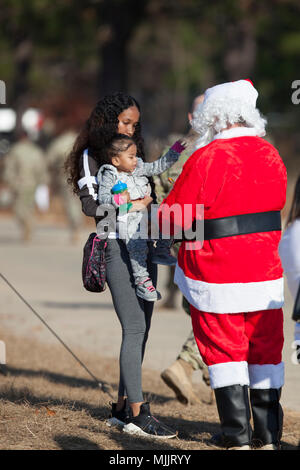 Kinder erwarten gespannt die Ankunft von Santa Claus, wie er weg geht der Drop Zone während des 20. jährlichen Randy Oler Memorial Betrieb Spielzeug Fallen, bewirtet durch die US-Armee die zivilen Angelegenheiten & psychologische Operations Command (Airborne), 01.12.2017. Betrieb Spielzeug Drop ist der weltweit größte kombinierten Betrieb mit neun Partner nation Fallschirmjäger teilnehmenden und Soldaten erlaubt, die Möglichkeit, auf ihren militärischen beruflichen Spezialgebiet zu trainieren, pflegen ihre Bereitschaft, in die Luft und wieder zurück in die lokale Gemeinschaft zu geben. (U.S. Armee Foto von John Jones) Stockfoto