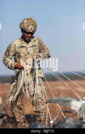 Ein Soldat der United States Army, der der 21st Military Police Company zugeteilt wurde, erholt sich am 1. Dezember 2017 während der 20th Annual Randy Ooler Memorial Operation Toy Drop in Fort Bragg, North Carolina, einen Fallschirm in der Sicily Drop Zone. Operation Toy Drop wird vom United States Army Civil Affairs and Psychological Operations Command (Airborne) veranstaltet und gilt als die größte kombinierte Luftlandeoperation weltweit. Das Archivbild dokumentiert multinationale Flugtraining, an dem acht Partnerländer beteiligt sind. Stockfoto