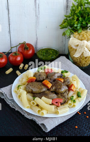 Pasta und gebratene Gänseleber (Huhn, Ente) mit Pesto und Tomate. Stockfoto