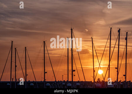 Segelboot Masten und Menschen zu Fuß auf einem Deich im Sonnenuntergang an der neuen Marina in Cadzand-Bad Stockfoto