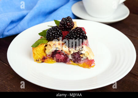 Ein Stück der Torte (Tart) mit frischen Brombeeren und Himbeeren, Baiser, Minze Dekoration auf einer weißen Platte Stockfoto