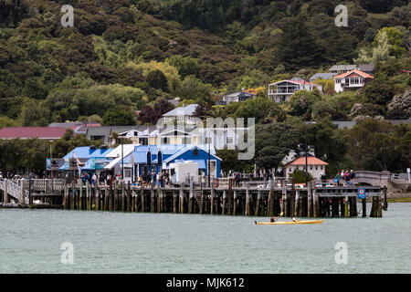 AKAROA, NEUSEELAND - 20 November, 2017: Touristen schlendern und vermischen sich auf dem Pier in Akaroa, ein Kreuzfahrtschiff, das Ziel auf der Banks Halbinsel Stockfoto