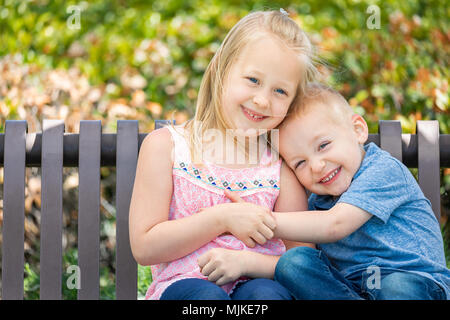 Junge Schwester und Bruder Spaß auf der Bank im Park. Stockfoto