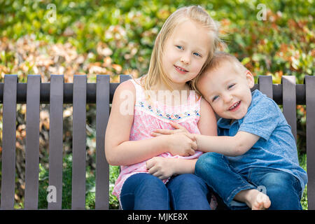 Junge Schwester und Bruder Spaß auf der Bank im Park. Stockfoto