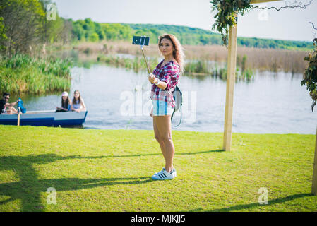 Bukarest, Rumänien, - Oktober 26, 2017: Frau, die selfie auf den Park in einem Sonntag. Junge Frau lächelnd, sitzend auf dem Gras. Illustrative editorial Stockfoto