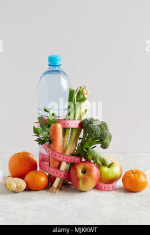 Flasche Wasser mit einem rosa Maßband, Gemüse und Obst. Konzept Gesundheit, Diät und Ernährung. Stockfoto