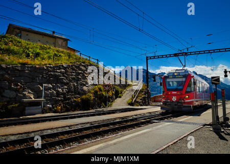 Poschiavo, Graubünden, Schweiz - 10 AUGUST 2016: Rote Zug der Rhätischen Bahn Einfahrt in die Station Alp Grum an einem sonnigen Tag im Sommer Stockfoto