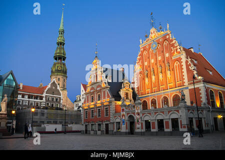 Riga, Lettland. Haus der Mitesser Gebäude, Melngalvju nams, mit Blick auf den Turm der St. Peter Kirche in Riga. Nacht stadtbild der Altstadt von Riga. Stockfoto