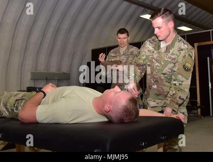 Staff Sgt. David Dillow, 386 Expeditionary medizinische Gruppe physikalische Therapie Techniker, Maßnahmen der rechten Schulter Bewegungsbereich des älteren Flieger Calvin Lourens, 386 Expeditionary Logistik Bereitschaft Squadron Passenger Service Specialist, Dez. 7, 2017, während Kapitän Eric Walter, 386 EMDG-physikalische Therapie element Chief, beobachtet an einem geheimen Ort im Südwesten Asien. (U.S. Air Force Foto von Tech. Sgt. Louis Vega Jr.) Stockfoto