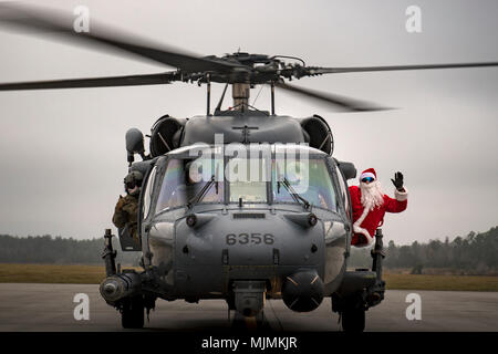 Santa wirft mit der Besatzung eines HH-60G Pave Hawk vom 41. Rescue Squadron, Dez. 9, 2017, auf der Flightline bei Moody Air Force Base, Ga. Jedes Jahr Santa seinen großen Auftritt macht mit dem Hubschrauber zur 23d und 347 Rettung Gruppe Holiday Party, wo er Posen für Fotos mit den Kindern und hört zu Weihnachten wünschen Listen teilnehmen. (U.S. Air Force Foto: Staff Sgt. Ryan Callaghan) Stockfoto