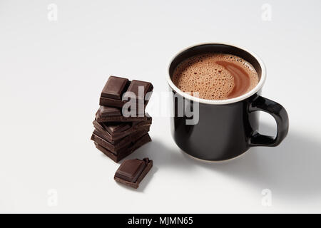 Schwarzer Kaffeebecher mit heißer Schokolade serviert mit Chunks von dunkler Schokolade Stockfoto