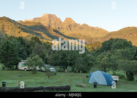 MONKS COWL, SÜDAFRIKA - 18. MÄRZ 2018: ein Zelt-, Caravan- und Fahrzeug auf dem Campingplatz bei Monks Cowl in den Drakensbergen. Cathedral Peak (links) und Stockfoto