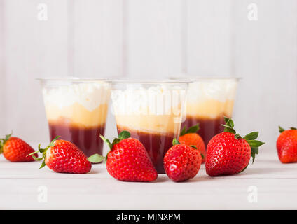 Kunststoffbehälter mit Erdbeer creme Dessert auf Holzuntergrund mit frischen Erdbeeren Stockfoto