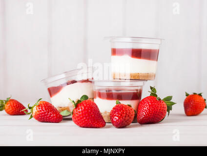 Kunststoffbehälter mit Erdbeer creme Dessert auf Holzuntergrund mit frischen Erdbeeren Stockfoto
