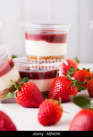 Kunststoffbehälter mit Erdbeer creme Dessert auf Holzuntergrund mit frischen Erdbeeren Stockfoto