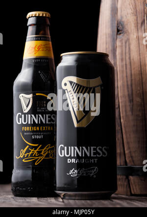 LONDON, Großbritannien - 03.Mai 2018: Aluminium und Glas Flasche Guinness Stout Bier neben Holzfass auf dunklem Hintergrund. Guinness Bier Stockfoto