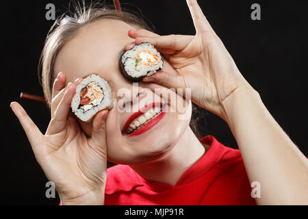 Spaß Frau zeigen Sushi in ihr Gesicht Nahaufnahme Portrait auf schwarzem Hintergrund Stockfoto