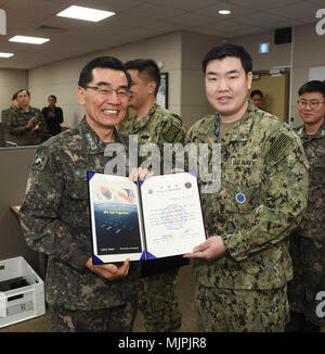 171221-N-TB 148-012 BUSAN, Republik Korea (31. 21, 2017) Republik Korea (ROK) Navy Vice Adm. Jung, Jin-Sup, Commander, ROK-Flotte, präsentiert Leutnant John Lee mit einem Brief der Termin für seine Auswahl an den "großen Jungen Köpfe "Junior Officers' Engagement und Zusammenarbeit. Die Initiative "grossen Jungen Köpfe' vereint hand-selektierte, junge Offiziere von der ROK und der US-Marine und sie vor die Aufgabe, innovative Lösungen für das ROK-US-Allianz der Zukunft weiter entwickeln. (U.S. Marine Foto von Mass Communication Specialist Seaman William Carlisle) Stockfoto