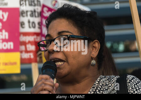 London, Großbritannien. 5. Mai 2018. Eine Immigration Anwalt liest ein Gedicht, das Sie über den Windrush Erfahrung in kalten feuchten England anreisen und erleben raciism am Protest außerhalb des Home Office für Theresa's Mai 2014 rassistische Zuwanderungsgesetz aufgehoben und ein sofortiges Ende der Deportation und Inhaftierung von Commonwealth citizens, mit denen bereits abgeschoben nach Großbritannien gekauft werden geschrieben hat. Sie forderten, die für alle Bürger des Commonwealth und für die Betroffenen für die Deportation kompensiert gewährleistet zu sein, Bedrohungen der Abschiebung, Inhaftierung, Verlust von Gehäuse, Jobs, Stockfoto