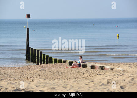 Boscombe, Bournemouth, Dorset, UK, 6. Mai 2018, Wetter: Morgen Sonnenschein an der Südküste auf, was die heißesten Mayday Bank Holiday Wochenende festgehalten werden könnte. Eine Frau entspannen am Strand neben einem ruhigen Meer. Stockfoto