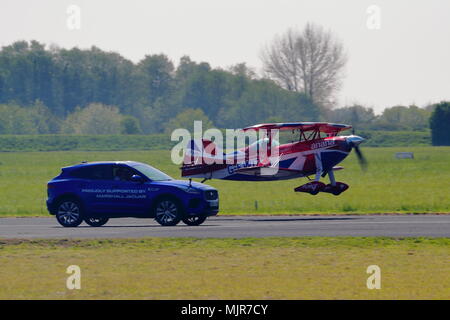 Oxfordshire, UK, 6. Mai 2018. Der waghalsige Pilot Richard Goodwin flog seinen Pitts Special Doppeldecker neben einem Jaguar F-Tempo entlang der Start- und Landebahn in Abingdon. Dies war das erste Mal in dieser Stunt im Vereinigten Königreich gezeigt wurde. Stockfoto